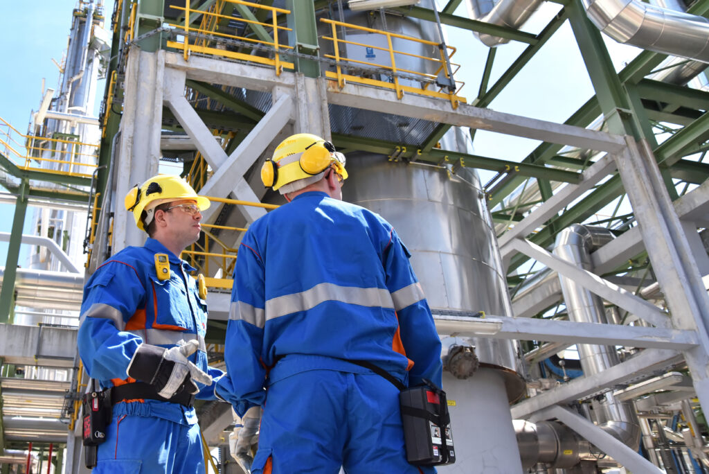Group of industrial workers in a refinery oil processing equipment and machinery